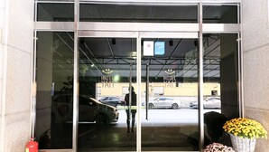 Ein Hotel Eingang mit Glastüren, einem Feuerlöscher und einem Parkplatz, der durch die Türen sichtbar ist.