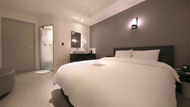 Ein modernes Hotelzimmer mit einem großen Bett, einem Schminktisch mit Spiegel und einem separaten Badezimmer.