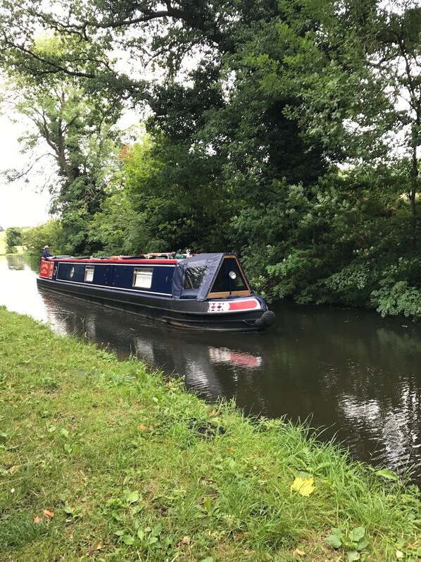 A narrowboat moored beside a river, surrounded by dense greenery and trees. - The Stable at New Wood Farm. Private parking behind electric gates. (Stourbridge)