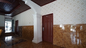 Un hall d’entrée spacieux, doté d’un haut plafond, d’un papier peint à motifs et d’un plancher poli.