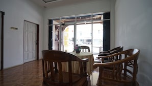 Une pièce avec un sol carrelé, une porte blanche, une fenêtre donnant sur l’extérieur et une table avec des chaises.