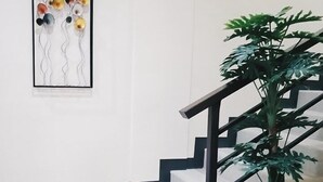 A staircase with a modern design, a potted plant, and a framed artwork on the wall. - Downtown Suites (Cagayan de Oro)