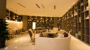 A modern interior with a seating area, a bookshelf, and a dining space. - New Century Life Hotel Changchun (Changchun)