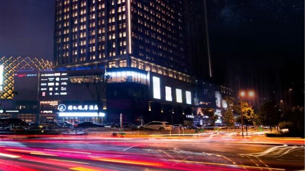 A high-rise building with illuminated signage at night. - New Century Life Hotel Changchun (Changchun)