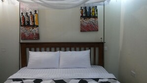 Una cama con almohadas blancas y una colcha de diseño blanco y negro. Dos cuadros adornan la pared sobre la cama.