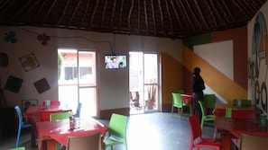 Una habitación con techo alto, un televisor montado en la pared y una persona de pie cerca de la puerta.