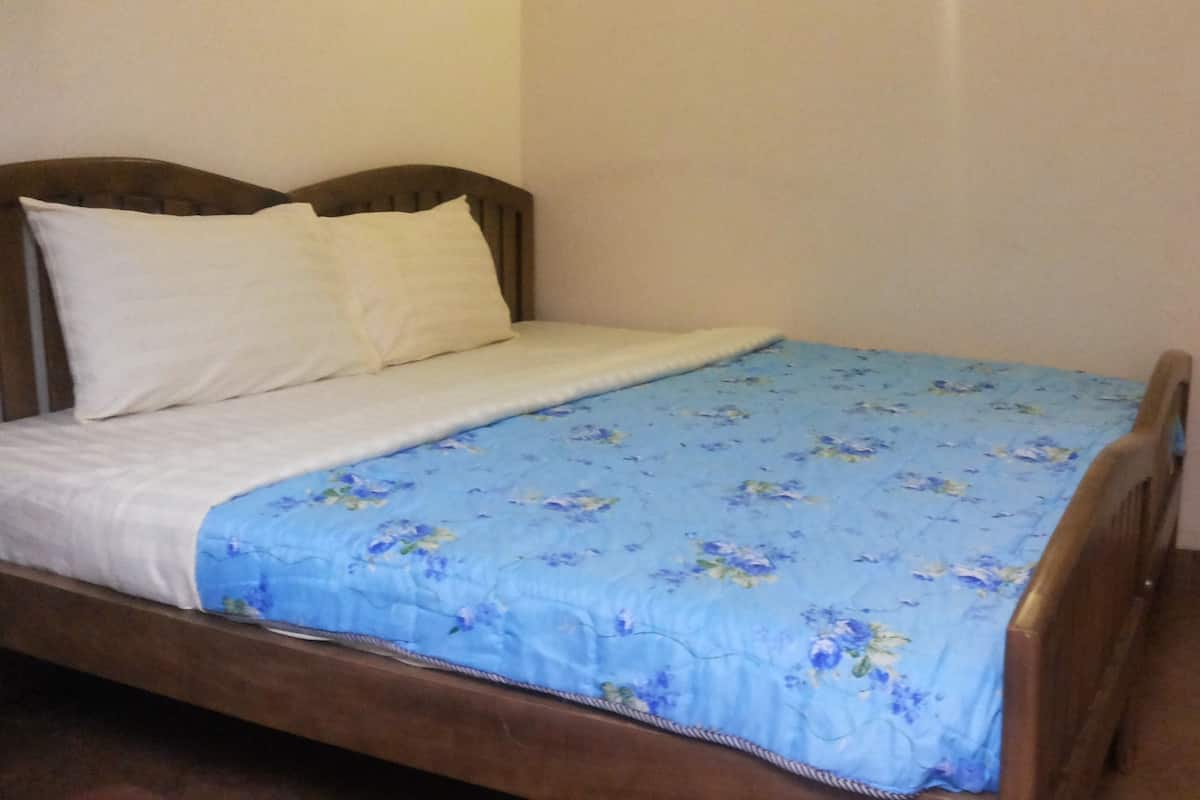 A single bed with a wooden frame, white bedding, and a blue floral bedspread.