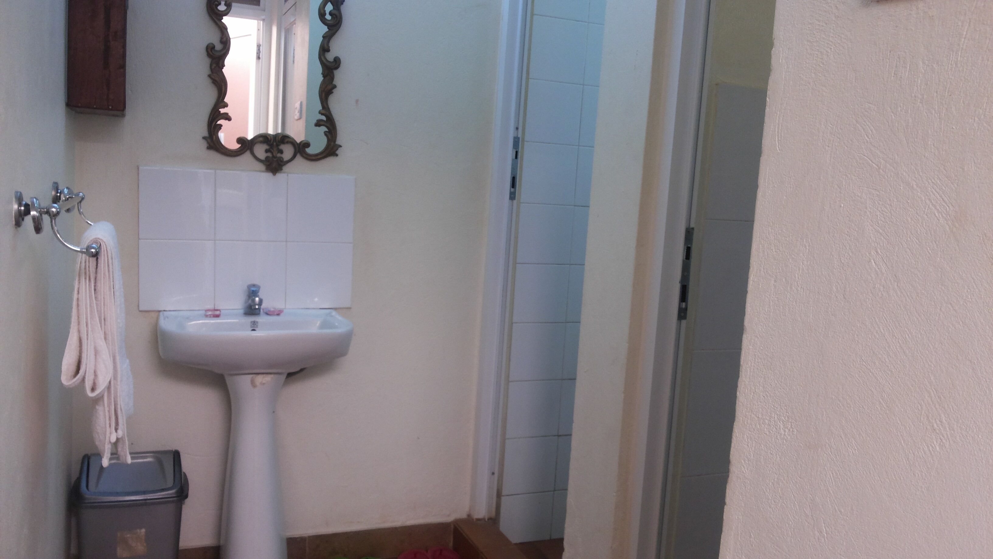 Ein Badezimmer mit einem weißen Waschbecken, einem Spiegel und einem Handtuch auf einem Haken.