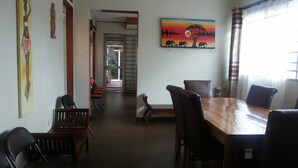 Un comedor con una mesa y sillas de madera, un cuadro en la pared y vistas al exterior a través de una ventana.