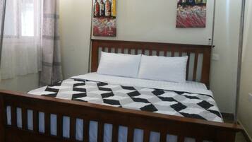 A bedroom with a wooden bed frame, a checkered bedspread, and two pillows.