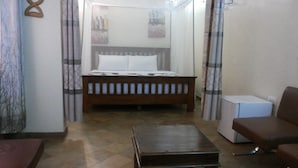Un dormitorio con una cama, una mesita, una silla y un armario blanco.