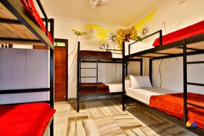 A bunk bed room with a wooden floor, a wall mural, and a ceiling fan. - Trippr Alleppey - Backpacker Hostel (Ambalapuzha)