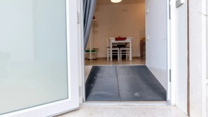 A doorway leading to a room with a small table and chairs, a bench, and a ceiling light.