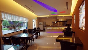A modern restaurant with a glass dining area, a kitchen in the background, and a view of the outdoors. - Kai-Hong Motel (Taoyuan City)