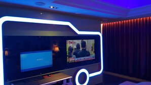 A room with a large screen displaying a video, a laptop, and a desk with a mouse and keyboard. - Kai-Hong Motel (Taoyuan City)