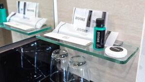 Een hotel receptie met een glazen balie waarop een fles Divine lotion, een witte doos en een witte tas met de merknaam staan.