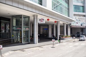 Entrada de un hotel con un letrero que dice 'HOTEL 7 Suria' y una señalización que indica 'ASCENSOR'.