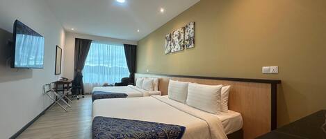 A hotel room with two beds, a TV, a desk, and a window with curtains.