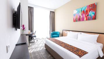 Ein Hotelzimmer mit einem großen Bett, einem Schreibtisch mit Stuhl, einem Fernseher und einem Gemälde an der Wand.