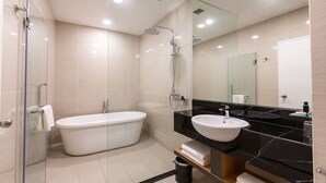 Een moderne badkamer met een douchecabine van glas, een vrijstaand bad en een wastafel van zwart marmer.