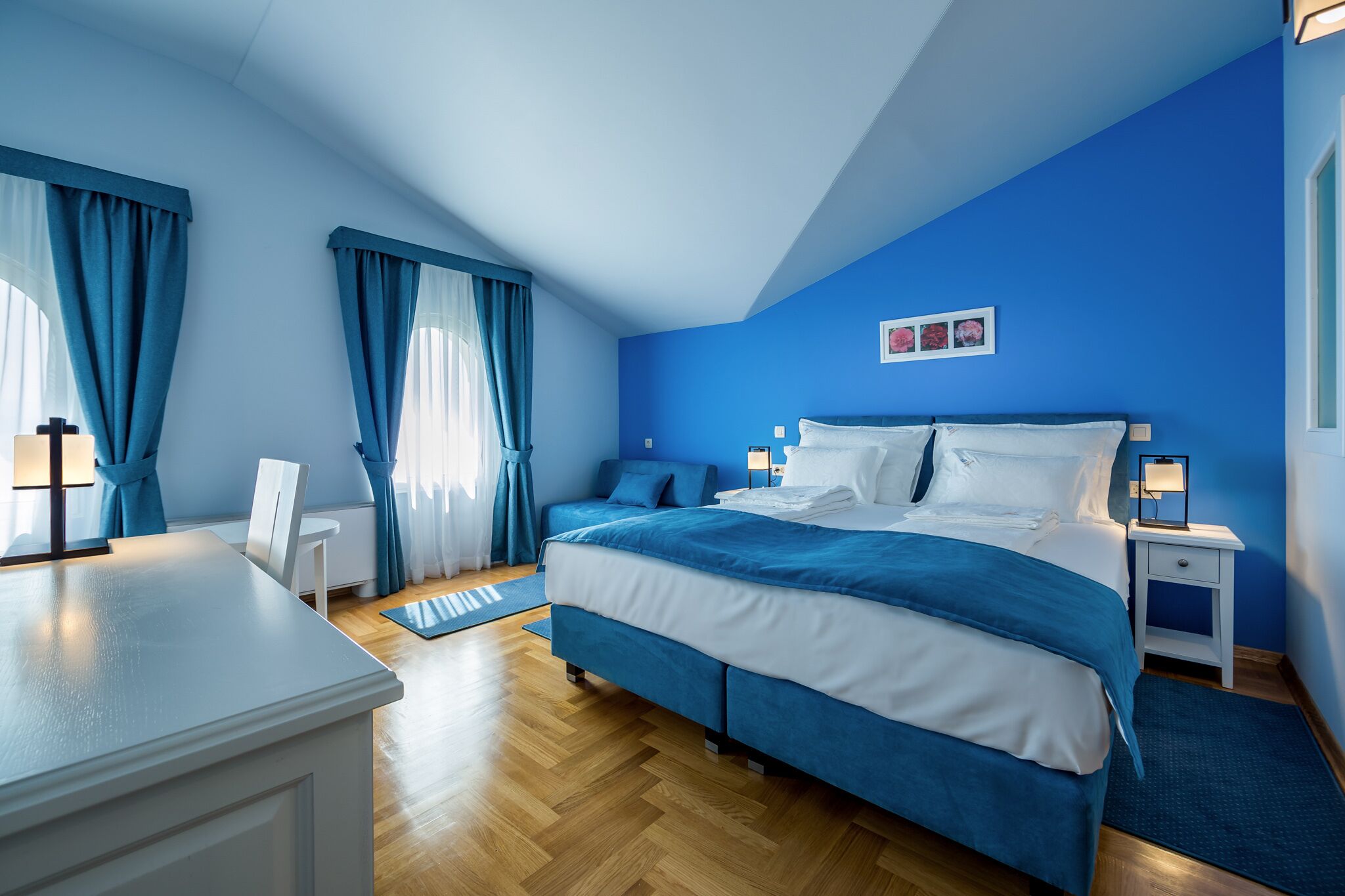 Ein Schlafzimmer mit Bett, Nachttischen, einem Sessel und Vorhängen.