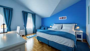 Ein Schlafzimmer mit Bett, Nachttischen, einem Sessel und Vorhängen.