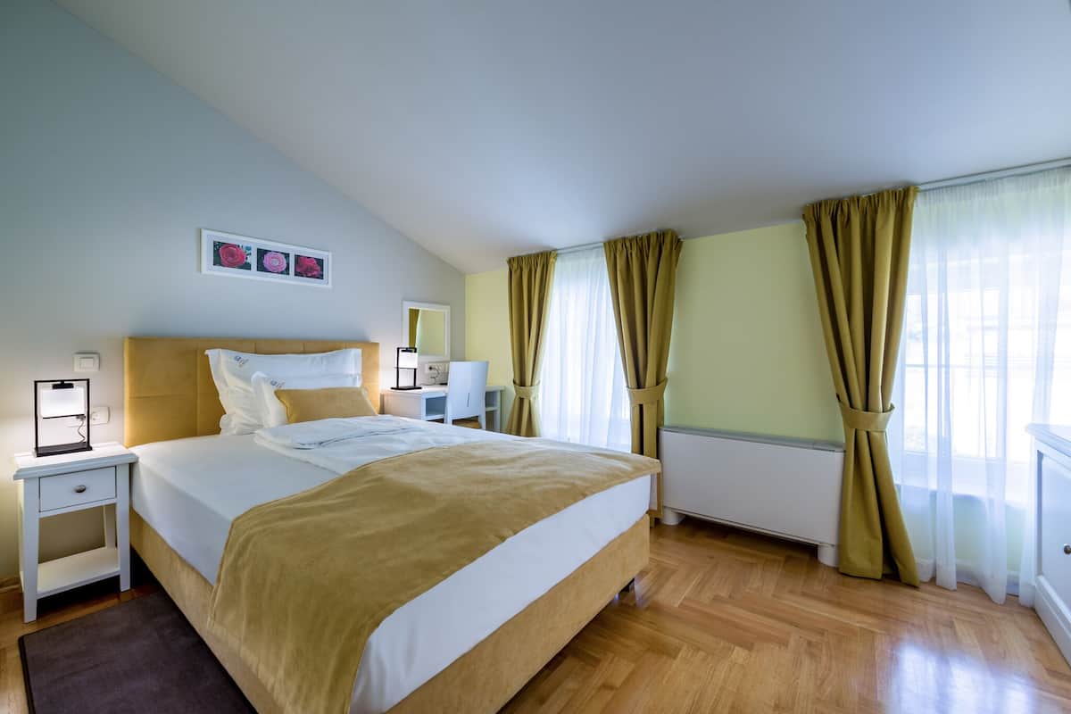 Ein ordentlich eingerichtetes Schlafzimmer mit einem großen Bett, Nachttischen, einem Schreibtisch und einer Heizung.
