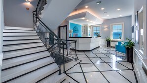 Un interior moderno con una escalera, un mostrador de recepción y vistas al mar.