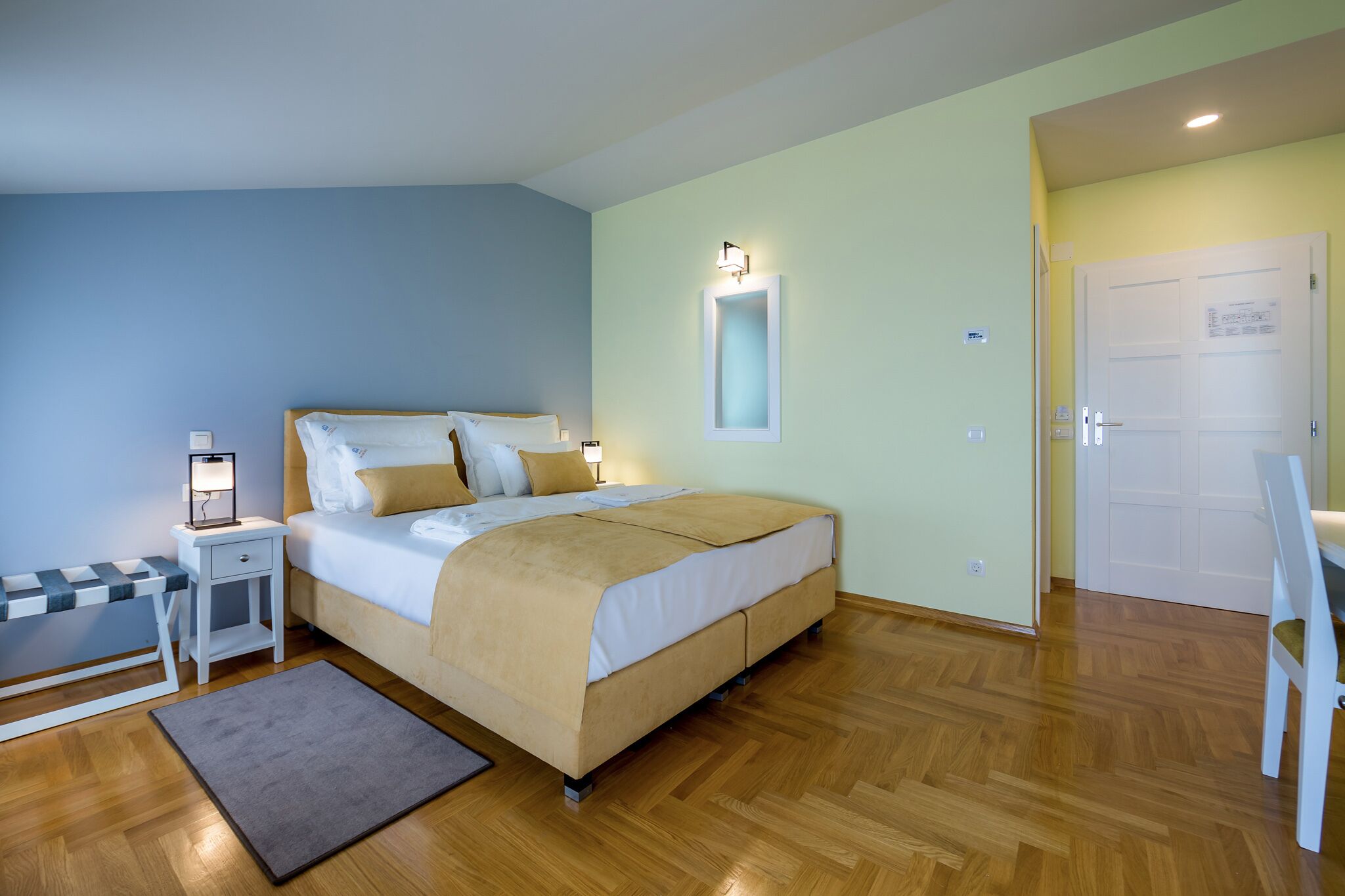 A bedroom with a bed, bedside table, lamp, and a bench.