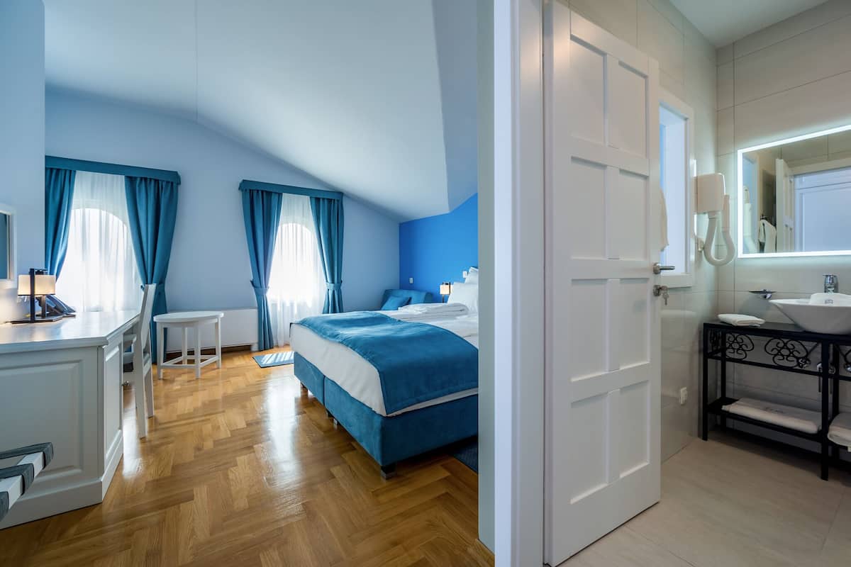 Ein Schlafzimmer mit Bett, Nachttisch und einem Badezimmer mit Waschbecken und Spiegel.