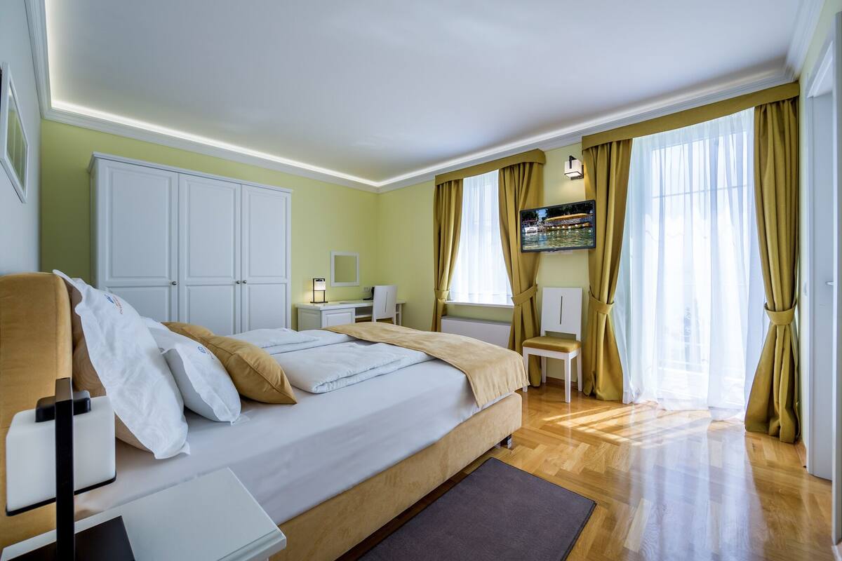 Ein modernes Hotelzimmer mit einem großen Bett, einem Schreibtisch, einem Stuhl und einem an der Wand befestigten Fernseher.