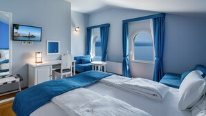 Habitación de hotel con cama, escritorio, silla, una mesita y televisor.