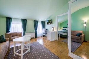 Ein Zimmer mit einer Couch, einem Schreibtisch, einem Sessel, einem Bett und einem großen Spiegel.