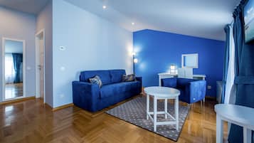Una sala moderna con un sofá azul, una mesita de centro blanca y un sillón azul.