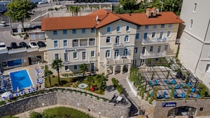 Un hotel con piscina, mobiliario exterior y una pared de piedra.