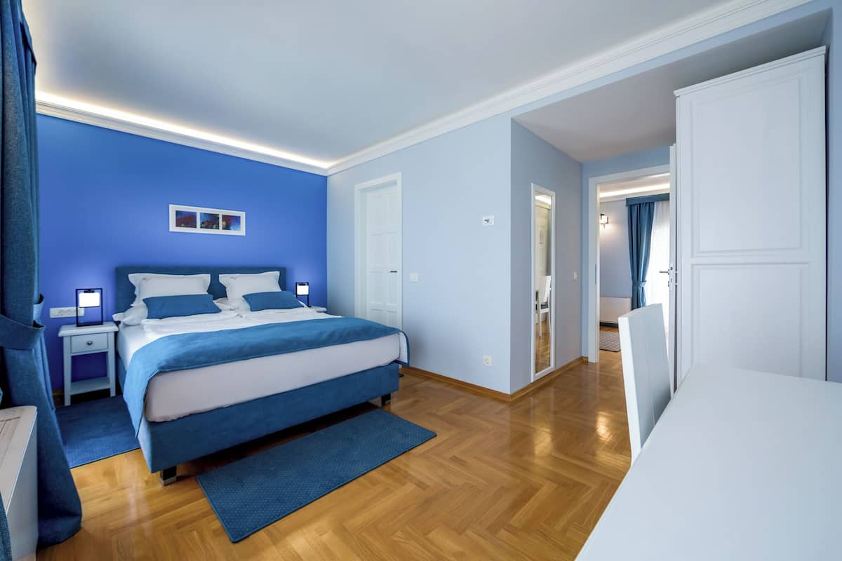 Ein modernes Schlafzimmer mit einem großen Bett, Nachttischen und einem begehbaren Kleiderschrank.