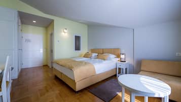 Quarto com cama, mesa de cabeceira, luminária e uma pequena mesa branca.