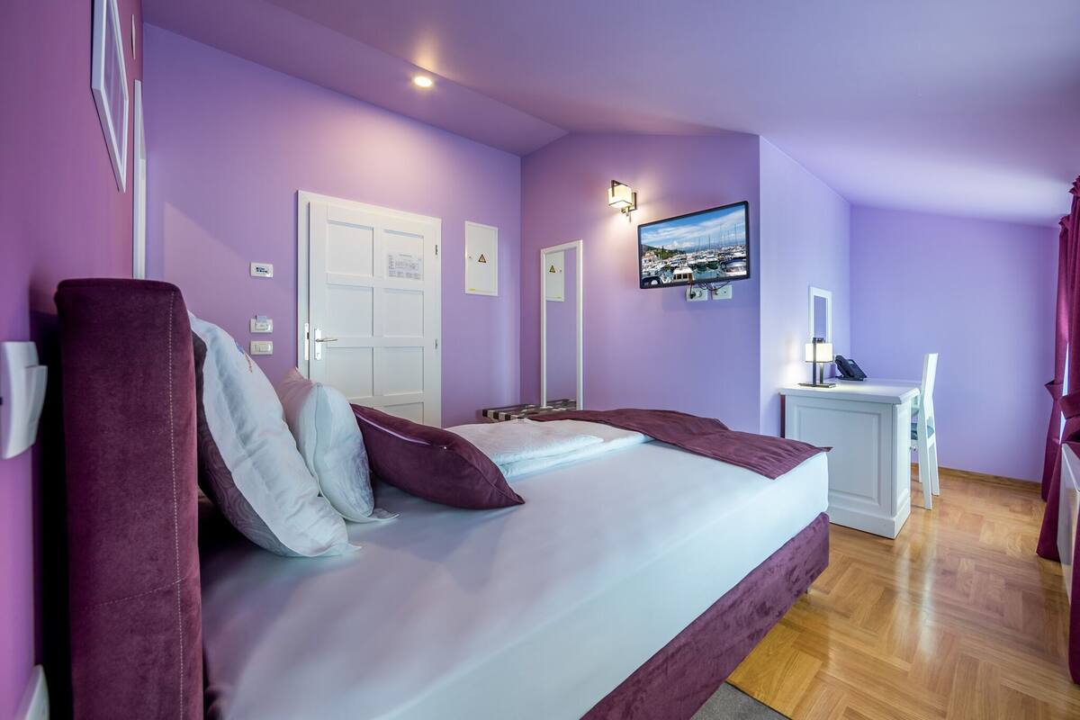Ein Schlafzimmer mit Bett, Schreibtisch, Stuhl und Fernseher an der Wand.