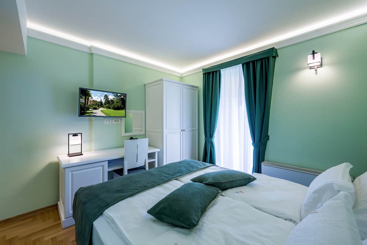Ein Hotelzimmer mit einem Bett, einem Schreibtisch, einem Fernseher und einem Kleiderschrank.