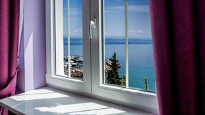 Una ventana con vistas a un paisaje costero, que incluye una masa de agua y tierra distante.