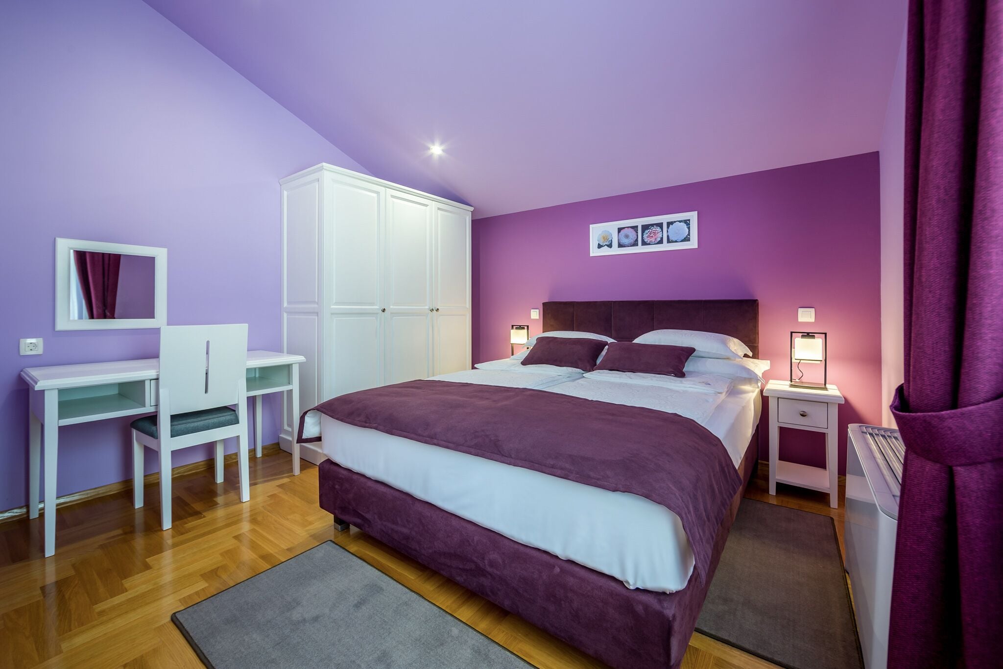 Ein Schlafzimmer mit Bett, Schreibtisch, Kleiderschrank und Nachttisch mit Lampe.