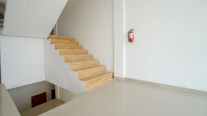 A staircase with wooden steps leading to a lower level. A fire extinguisher is mounted on the wall to the right. - OYO 1146 Miracle Homestay Syariah (Palembang)
