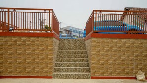 A set of stone steps leading up to a gated entrance with a blue car parked nearby. - OYO 1146 Miracle Homestay Syariah (Palembang)