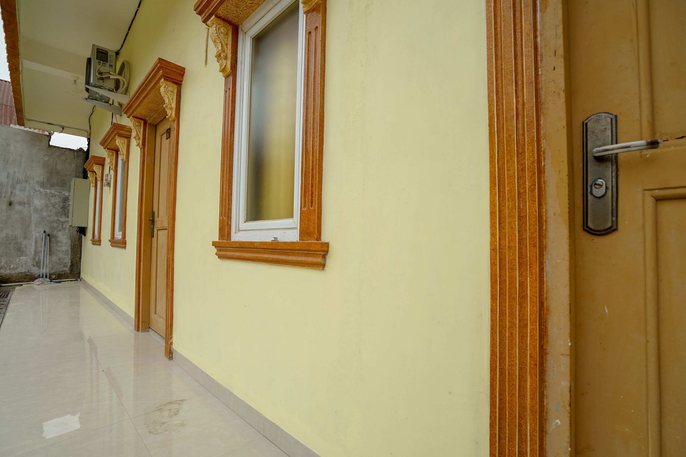 A hallway with doors and windows, a tiled floor, and a wall-mounted air conditioning unit.
