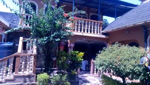 A traditional building with a covered entrance, a balcony with a balustrade, and a staircase leading to the upper level. - Penthouse Inn (Moyo)