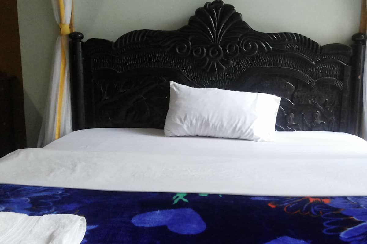 A bed with a dark headboard, white bedding, and a floral-patterned bedspread.