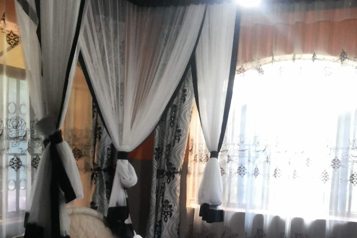 A bedroom with a bed, curtains, and a ceiling fan.