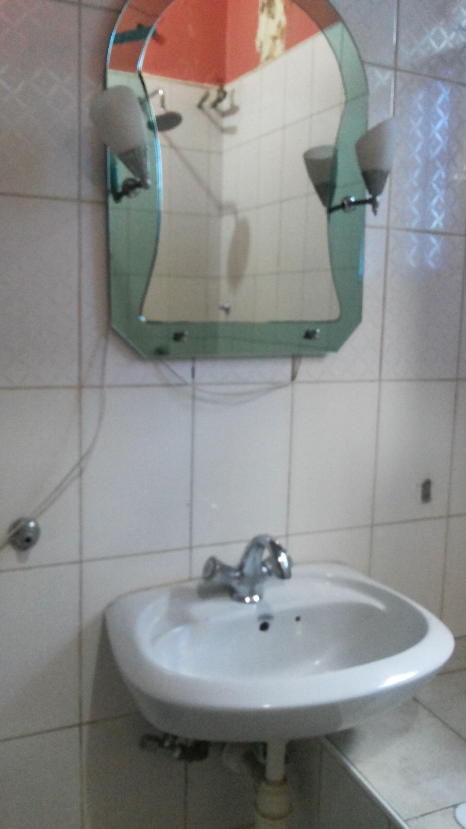 A bathroom with a white sink, a mirror, and a tiled wall.