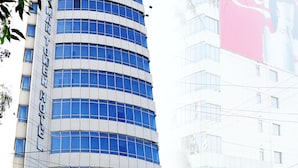 Un hotel moderno con fachada curva, ventanas amplias y un cartel para el Restaurante y Salón de Banquetes Shalimar Tower Hotel.