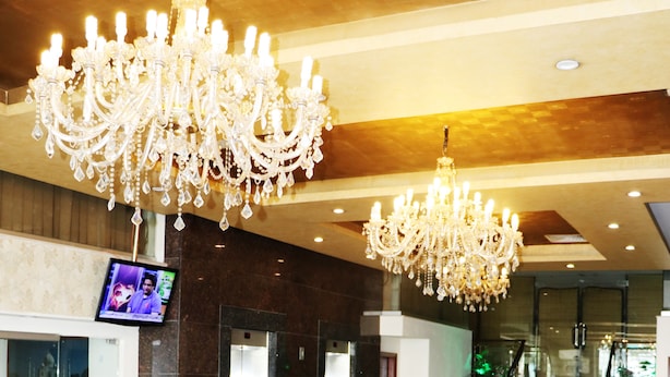 Un vestíbulo con candelabros, televisor, ascensores y escalera.